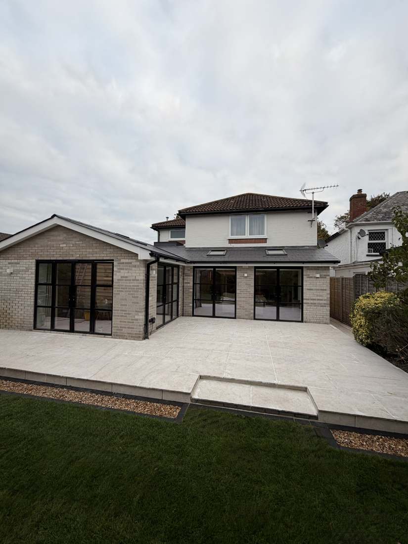 After: new brick extension with black framed doors, porcelain patio and lawn